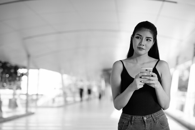 Retrato de uma jovem e bela mulher asiática explorando a cidade em preto e branco