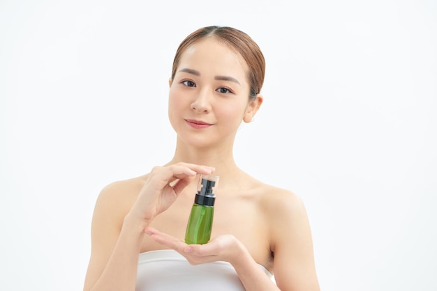 Retrato de uma jovem e bela mulher asiática mostrando uma garrafa verde de produto cosmético na mão