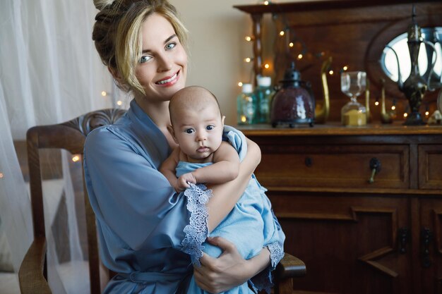 Retrato de uma jovem e linda mãe com seu bebê fofo embrulhado no pano azul