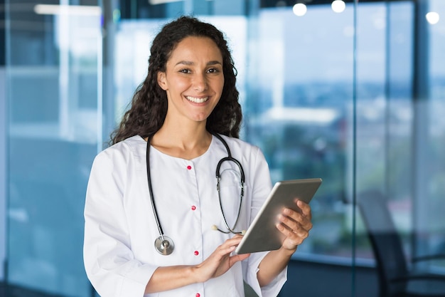 Retrato de uma jovem e linda médica com um tablet, uma médica hispânica trabalhando em