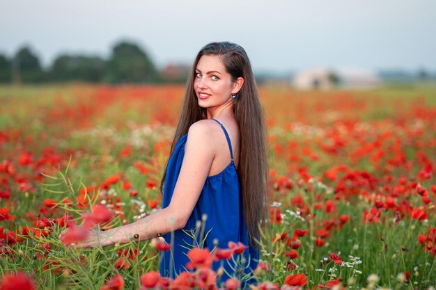 Retrato de uma jovem elegante no campo de papoulas à luz do sol à noite