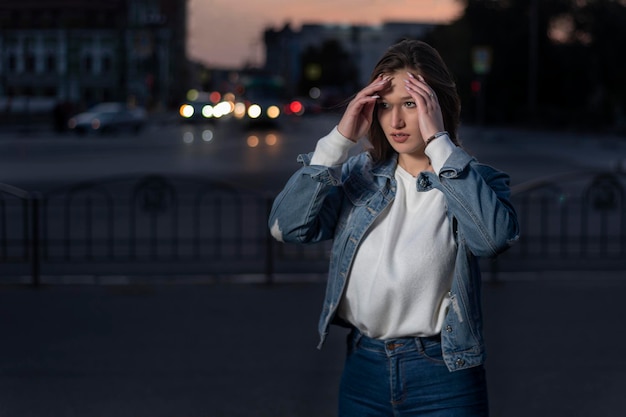 Retrato de uma jovem elegante no fundo da cidade à noite Jovem caminhando na rua da cidade