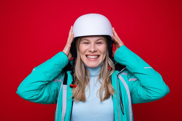 Retrato de uma jovem em um capacete de esqui em um fundo vermelho esqui e snowboard