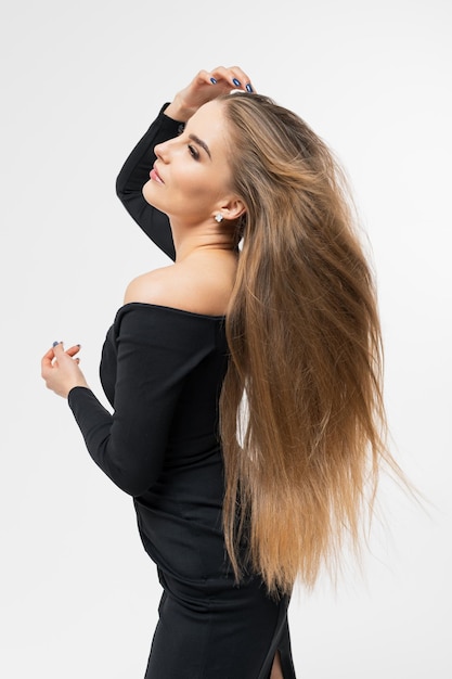 Retrato de uma jovem em um vestido preto com cabelo longo e bem cuidado Penteado para fotografia