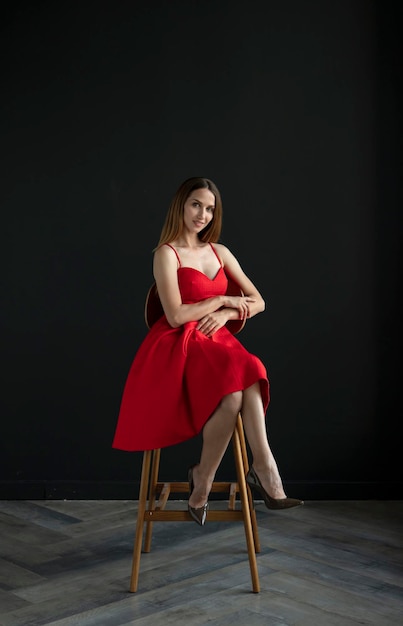 retrato de uma jovem em um vestido vermelho, sentado em um banco alto