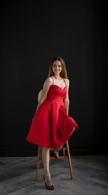 retrato de uma jovem em um vestido vermelho, sentado em um banco alto