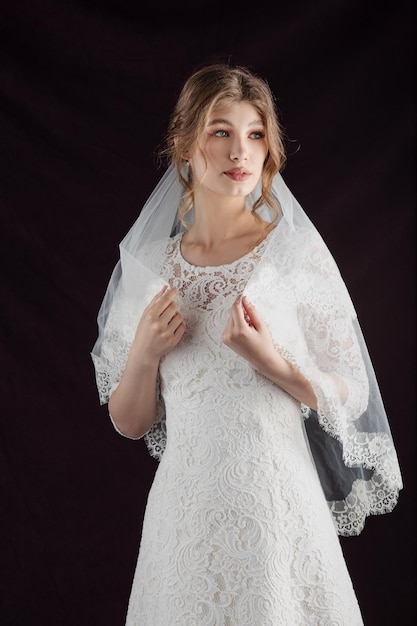 Retrato de uma jovem em uma imagem de casamento Penteado de casamento e maquiagem brilhante Uma elegante flor branca em suas mãos