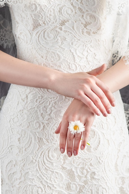 Retrato de uma jovem em uma imagem de casamento Penteado de casamento e maquiagem brilhante Uma elegante flor branca em suas mãos