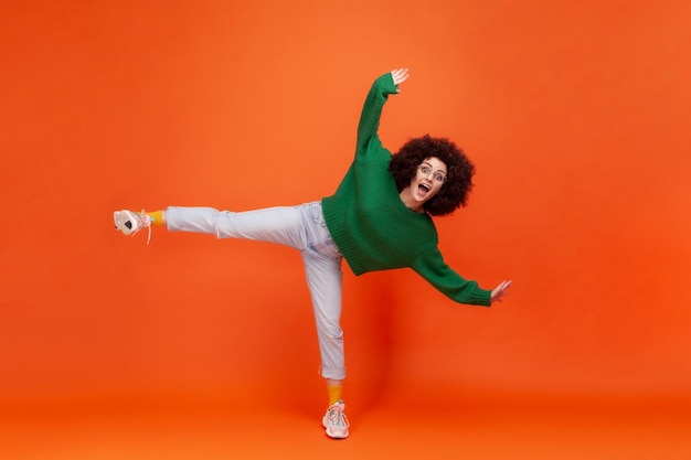 Retrato de uma jovem emocional de cabelo encaracolado em fundo laranja