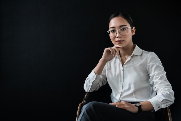 Retrato de uma jovem empresária asiática bonita sentada na frente do fundo preto