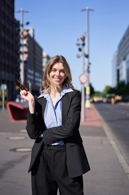 Foto retrato de uma jovem empresária bem-sucedida de terno preto em pé na rua ensolarada e sm