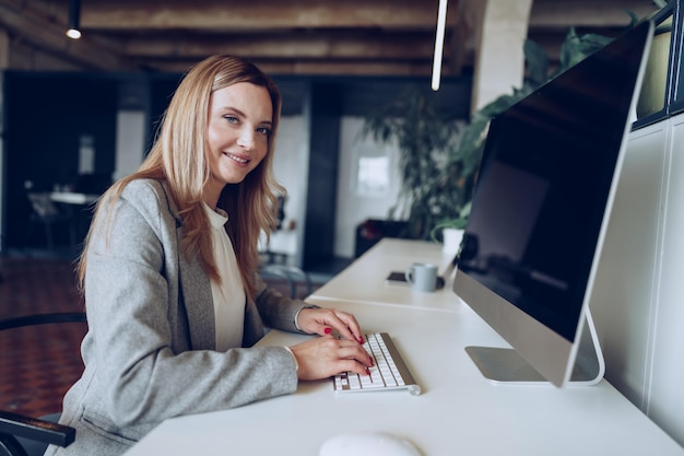 Retrato de uma jovem empresária inteligente sentada à mesa de trabalho no escritório