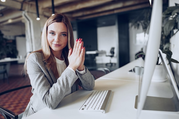 Retrato de uma jovem empresária inteligente sentada à mesa de trabalho no escritório