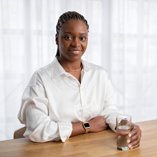 Retrato de uma jovem empresária negra bebendo água no escritório