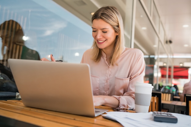 Retrato de uma jovem empresária trabalhando em seu laptop em uma cafeteria