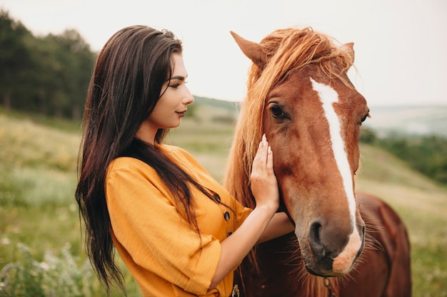 Retrato de uma jovem encantadora abraçando um cavalo. Linda mulher tocando um rosto de cavalo sorrindo.