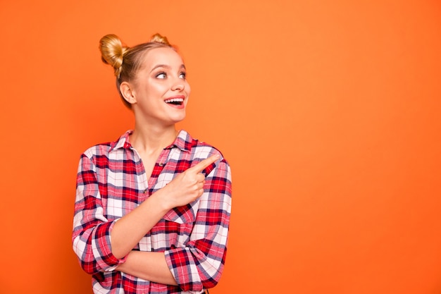 Retrato de uma jovem encantadora vestida com uma camisa xadrez xadrez isolada em laranja