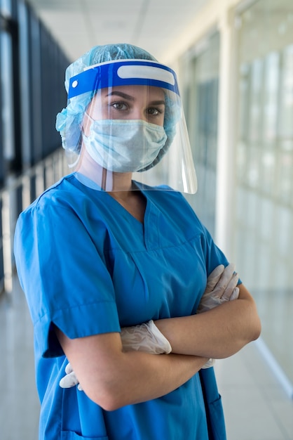 Retrato de uma jovem enfermeira em um uniforme azul e um escudo protetor para se proteger contra um novo vírus perigoso covid 19