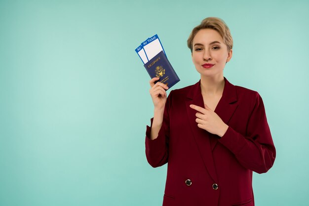 Retrato de uma jovem engraçada com passaporte e cartão de embarque sobre fundo azul. Abrindo fronteiras. Início das viagens aéreas após uma pandemia.