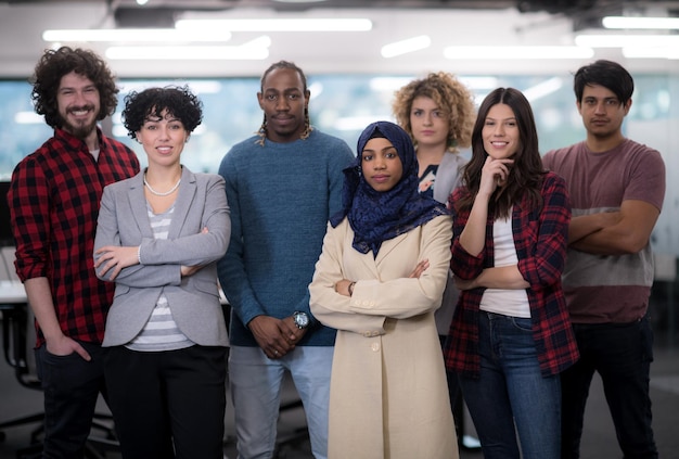 Retrato de uma jovem equipe multiétnica de desenvolvedores de software, de pé, olhando para a câmera, enquanto celebra o sucesso no escritório moderno de startups