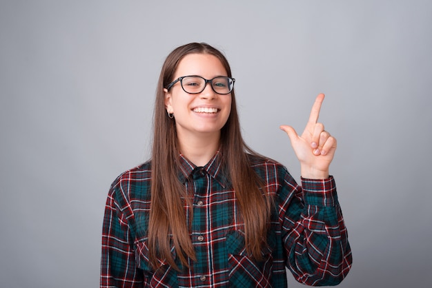 Retrato de uma jovem estudante encantadora apontando para outro lado