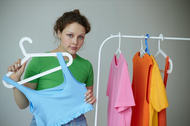 Retrato de uma jovem experimentando o guarda-roupa de roupas Fundo claro de estilo juvenil inalterado