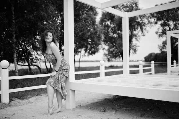 Retrato de uma jovem fabulosa vestindo roupa chique posando em um terraço de madeira branco Foto em preto e branco