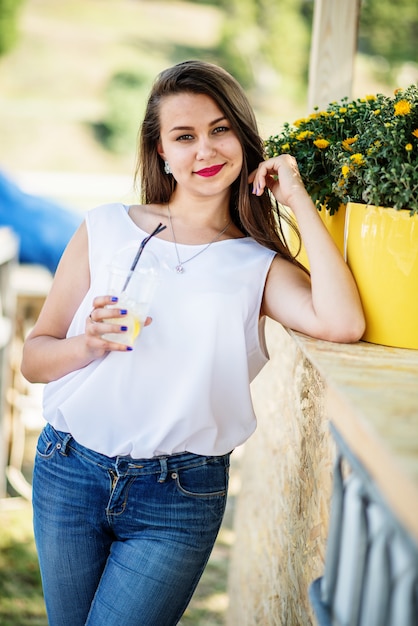 Retrato de uma jovem fantástica posando ao lado do vaso de flores lá fora no parque.