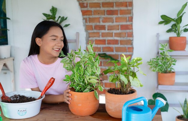 Retrato de uma jovem feliz com plantas verdes em casa, menina asiática