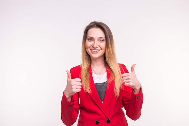 Retrato de uma jovem feliz com polegares para cima em uma jaqueta vermelha em estúdio