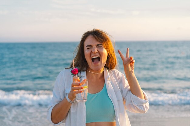 Foto retrato de uma jovem feliz com um coquetel na mão em um fundo de belo mar