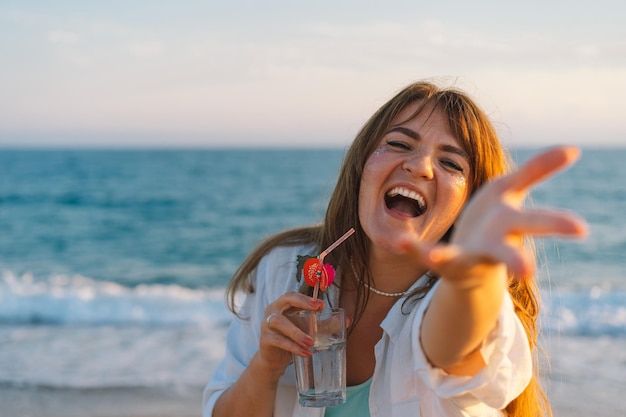 Retrato de uma jovem feliz com um coquetel na mão em um fundo de belo mar