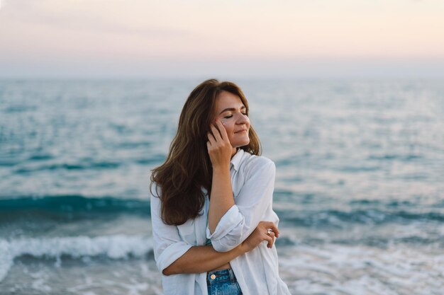 Retrato de uma jovem feliz em um fundo de lindo mar a garota olha para o mar mágico liberdade e felicidade