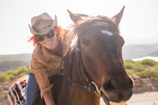 Retrato de uma jovem feliz montando um cavalo contra um céu claro durante um dia ensolarado