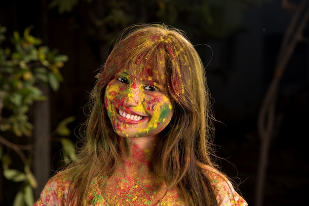 Foto retrato de uma jovem feliz no festival de cores holi. garota posando e comemorando o festival das cores.