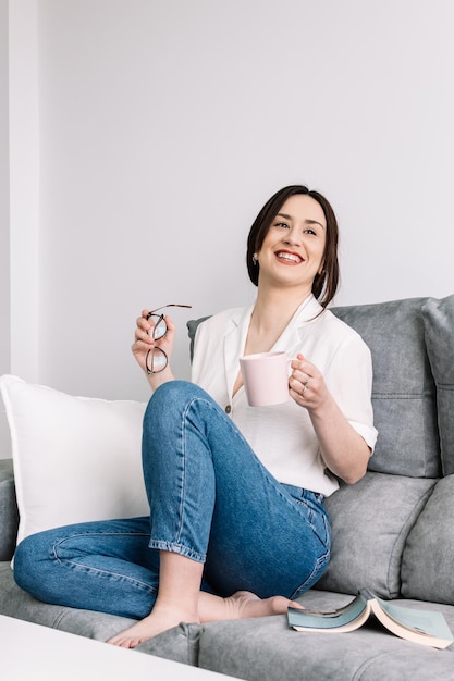 Foto retrato de uma jovem feliz segurando uma caneca em casa