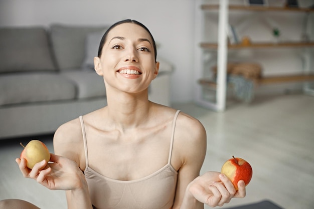 Retrato de uma jovem fitness em casa segurando maçãs frescas
