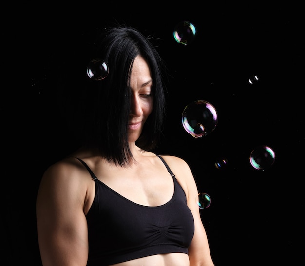 Retrato de uma jovem garota com cabelo curto preto e uma figura de esportes no escuro