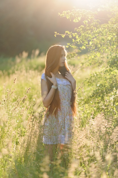 Retrato de uma jovem garota linda em um vestido de verão. Sessão de fotos de verão no parque ao pôr do sol. Close-up tiro.