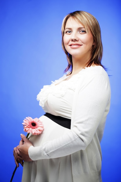 Retrato de uma jovem grávida feliz e sorridente com uma flor