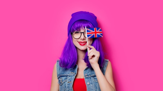 Retrato de uma jovem hipster com cabelo roxo e bandeira do Reino Unido em fundo rosa