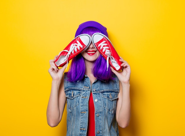Retrato de uma jovem hipster com cabelo roxo e sapatos vermelhos em fundo amarelo