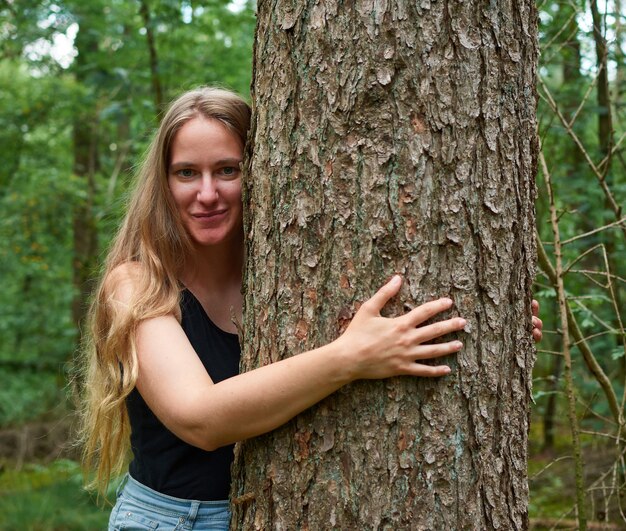 Retrato de uma jovem italiana abraçando uma árvore em uma floresta