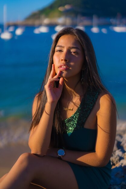 Retrato de uma jovem latina aproveitando o verão com um vestido verde à beira-mar