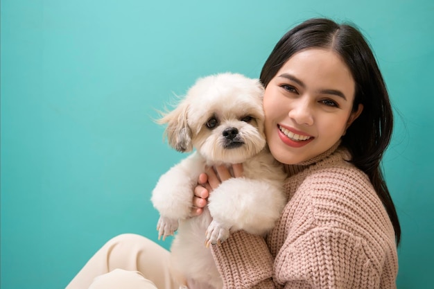 Retrato de uma jovem linda beija e abraça seu cachorro sobre fundo verde