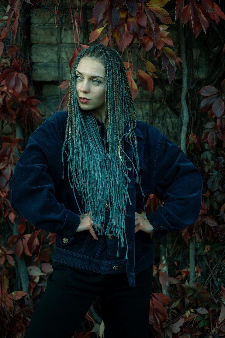Foto retrato de uma jovem linda com um sorriso no rosto em um parque de outono contra um fundo de folhas coloridas uma garota com dreadlocks e pigtails posa contra o fundo de árvores