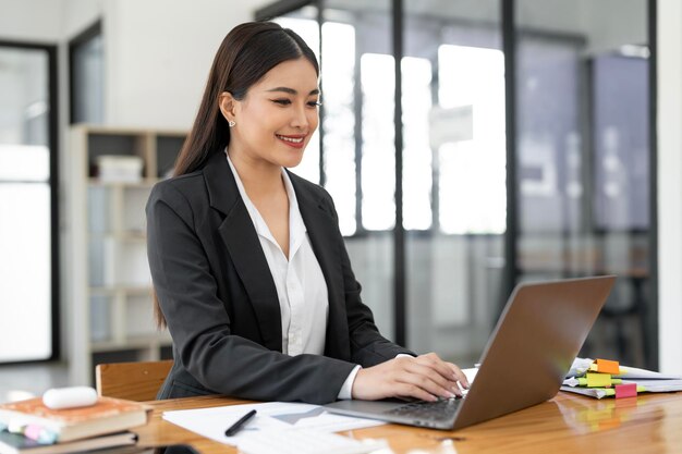 Retrato de uma jovem linda e alegre sorrindo enquanto trabalhava com laptop no escritório