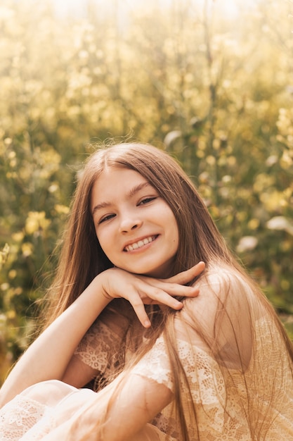 Retrato de uma jovem linda e feliz, com cabelo comprido no contexto de flores de colza. Juventude e natureza