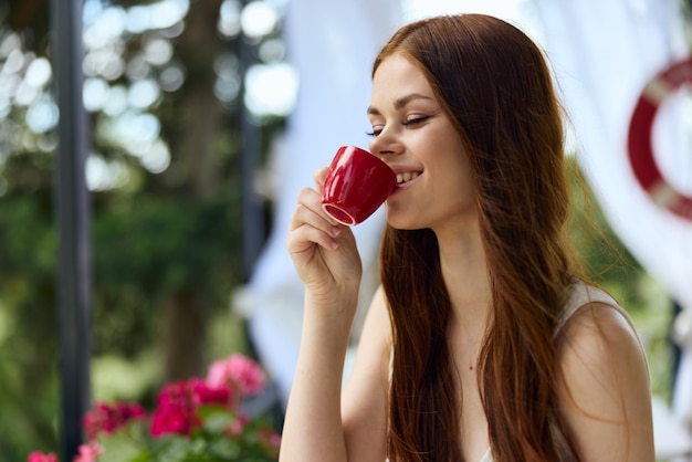 Foto retrato de uma jovem linda em um vestido branco bebe café ao ar livre em um café conceito de relaxamento