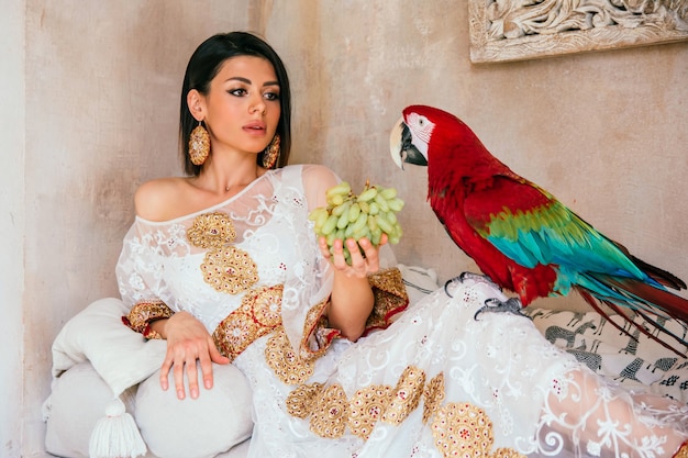 Retrato de uma jovem linda em um vestido branco com um papagaio